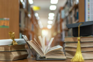 Online education course, E-learning class and e-book digital technology concept with pc computer notebook open in blur school library or classroom background among old stacks of book, textbook