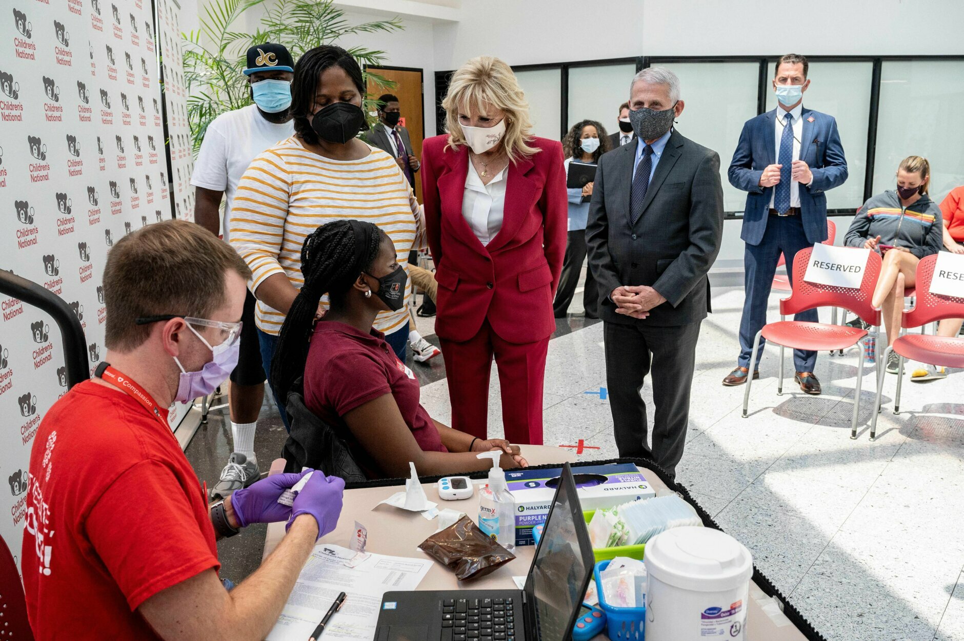 US First Lady Jill Biden (C) and Dr. Anthony Fauci (3rd R) speak with Skylah Jacksons (3rd L) family before her first Covid-19 vaccination in the vaccination center at the Children's National Hospital in Washington, DC on May 20, 2021. (Photo by JIM WATSON / AFP) (Photo by JIM WATSON/AFP via Getty Images)