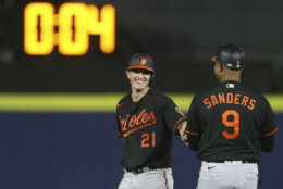 Baltimore Orioles' Austin Hays (21) smiles as he hands his gloves to first base coach Anthony Sanders (9) after hitting a two-RBI double during the eighth inning of a baseball game against the Toronto Blue Jays in Buffalo, N.Y., Friday, June 25, 2021. (AP Photo/Joshua Bessex)