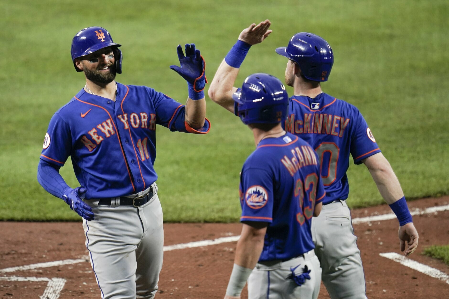 New York Mets' Kevin Pillar (11) is greeted near home pate by James McCann (33) and Billy McKinney after Pillar scored them all on a three-run home run off Baltimore Orioles starting pitcher Matt Harvey during the third inning of a baseball game, Wednesday, June 9, 2021, in Baltimore. (AP Photo/Julio Cortez)