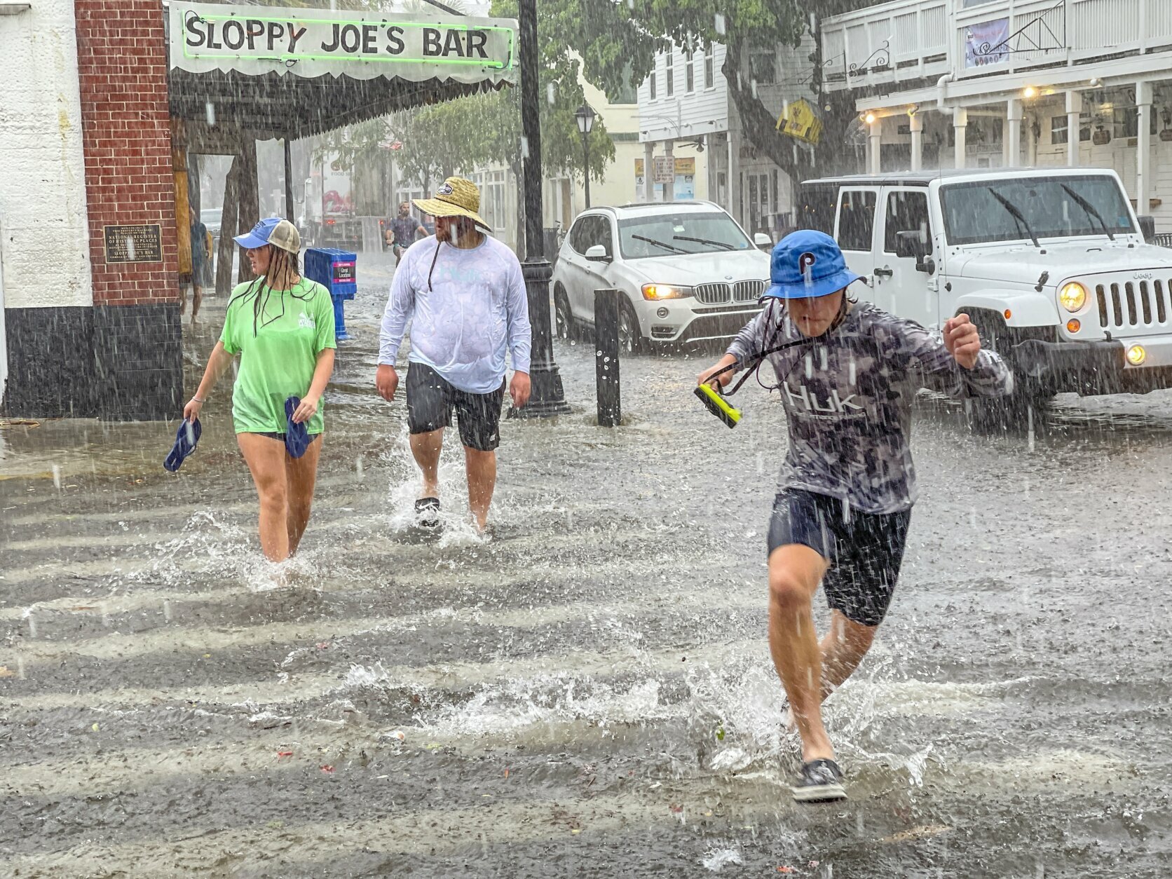 Pedestrians dash across the intersection of Greene and Duval streets as heavy winds and rain associated with Tropical Storm Elsa passes Key West, Fla., on Tuesday, July 6, 2021. The weather was getting worse in southern Florida on Tuesday morning as Tropical Storm Elsa began lashing the Florida Keys, complicating the search for survivors in the condo collapse and prompting a hurricane watch for the peninsula's upper Gulf Coast. (Rob O'Neal/The Key West Citizen via AP)