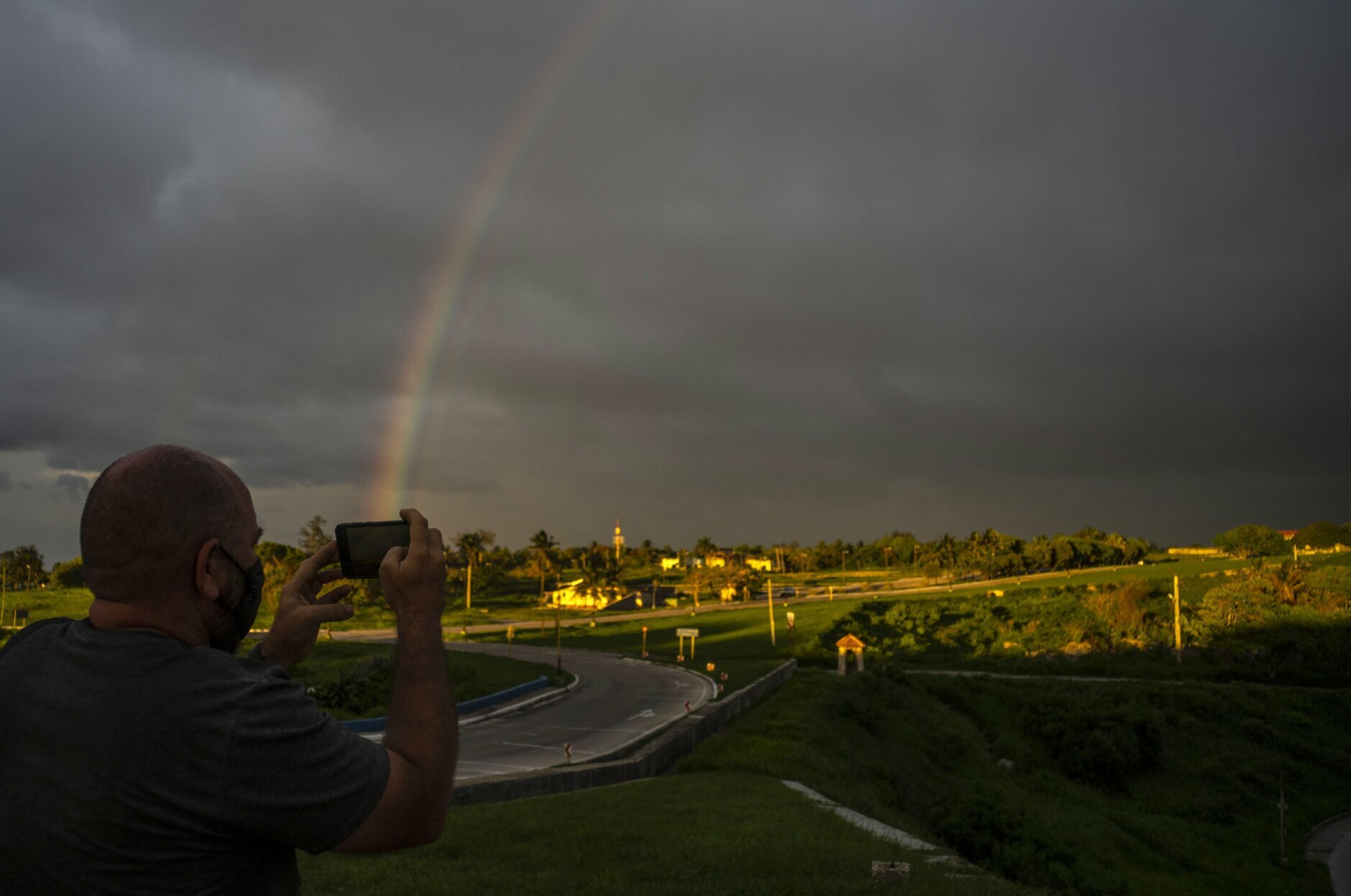 A photographer takes a photo with his cell phone of a rainbow that came out after of the passage of Tropical Storm Elsa, in Havana, Cuba, Monday, July 5, 2021. (AP Photo/Ramon Espinosa)