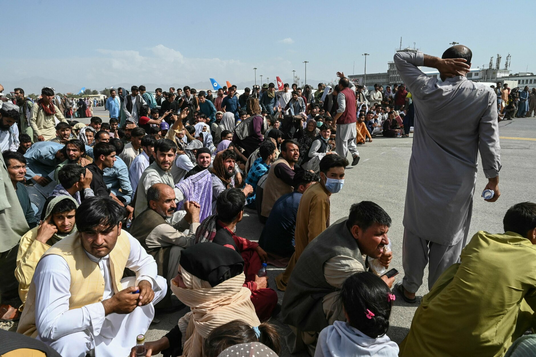 TOPSHOT - Afghan passengers sit as they wait to leave the Kabul airport in Kabul on August 16, 2021, after a stunningly swift end to Afghanistan's 20-year war, as thousands of people mobbed the city's airport trying to flee the group's feared hardline brand of Islamist rule. (Photo by Wakil Kohsar / AFP) (Photo by WAKIL KOHSAR/AFP via Getty Images)