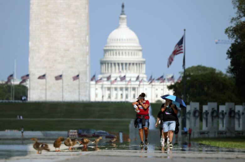 People walking in hot weather along the National Mall.