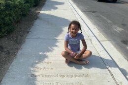 Takoma Park, Md. resident Aissatou Thiam, 7, sits next to her poem that was stamped into a sidewalk.