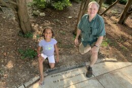 Richard Weil kneels near the lyrics of a song he wrote, that is now stamped into a sidewalk in Takoma Park, Md.