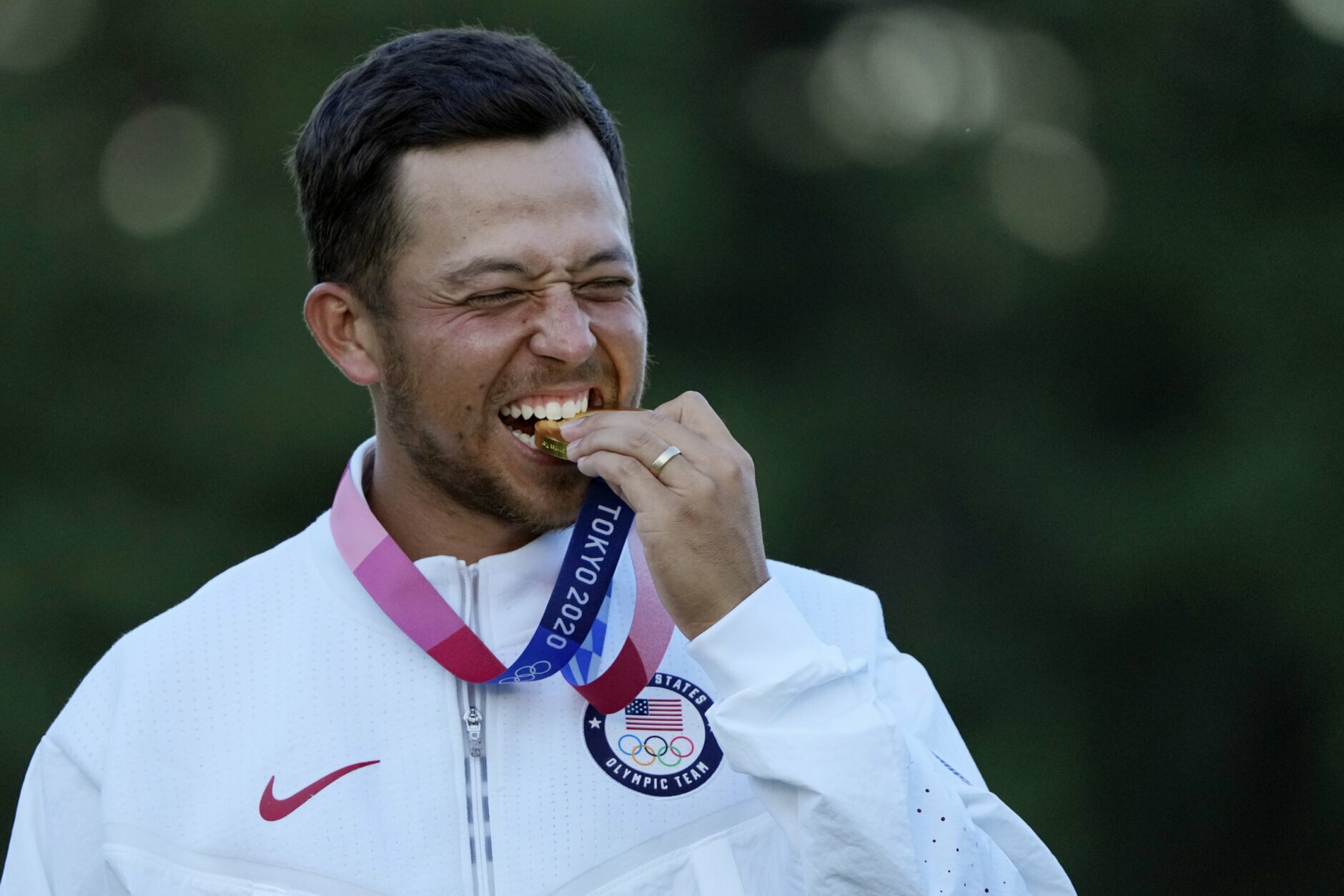 Xander Schauffele, of the United States, walks bites his gold medal in the men's golf at the 2020 Summer Olympics on Sunday, Aug. 1, 2021, in Kawagoe, Japan. (AP Photo/Andy Wong)