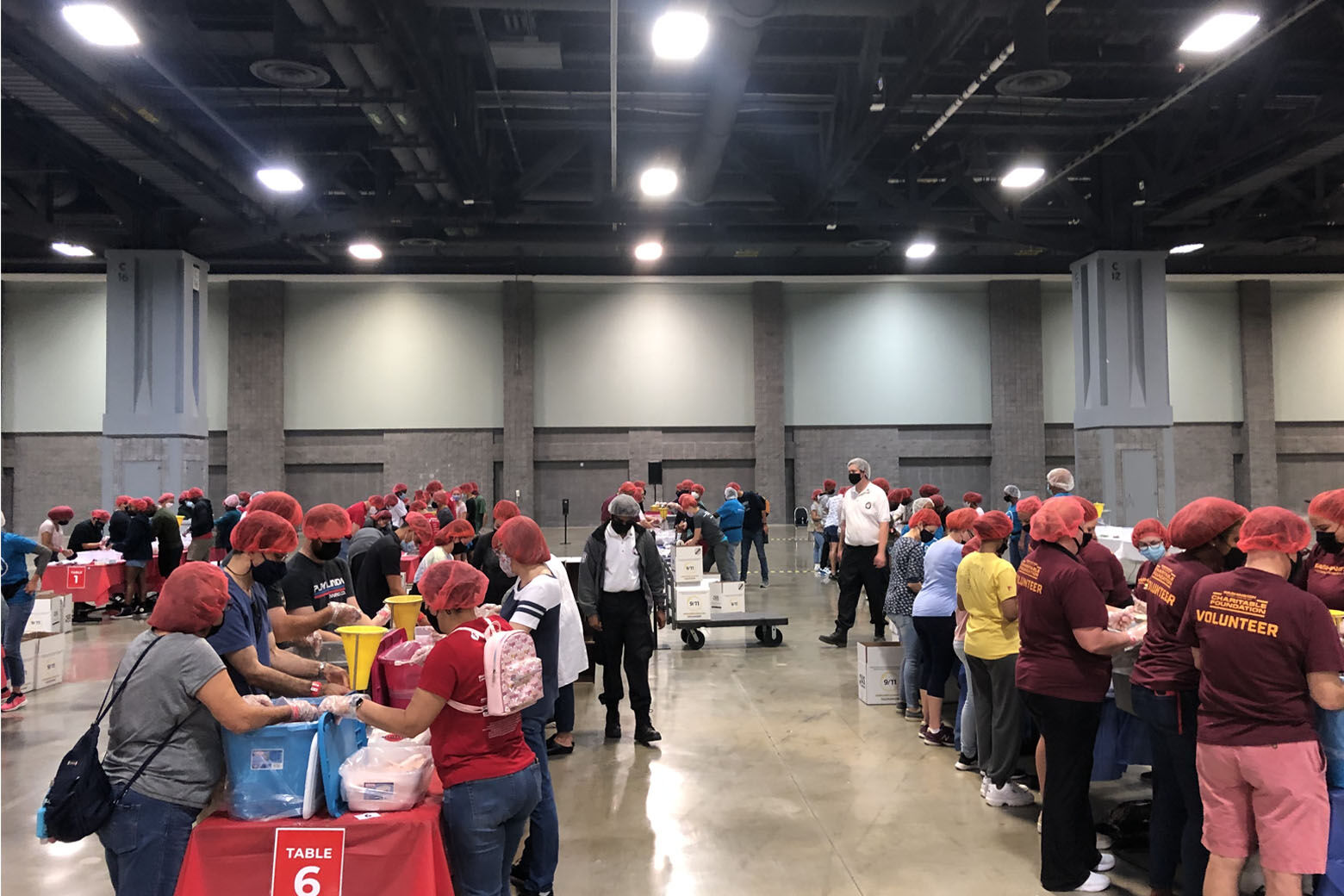 The volunteers stood elbow-to-elbow at long rows of banquet tables, their hands busy measuring, pouring, seasoning and packing as many as 200,000 meals.(WTOP/Dick Uliano)