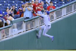 New York Mets left fielder Jeff McNeil (6) climbs the wall for a foul ball by Washington Nationals' Andrew Stevenson during the ninth inning of the first baseball game of a doubleheader, Saturday, Sept. 4, 2021, in Washington. The Mets won 11-9 in extra innings. (AP Photo/Nick Wass)