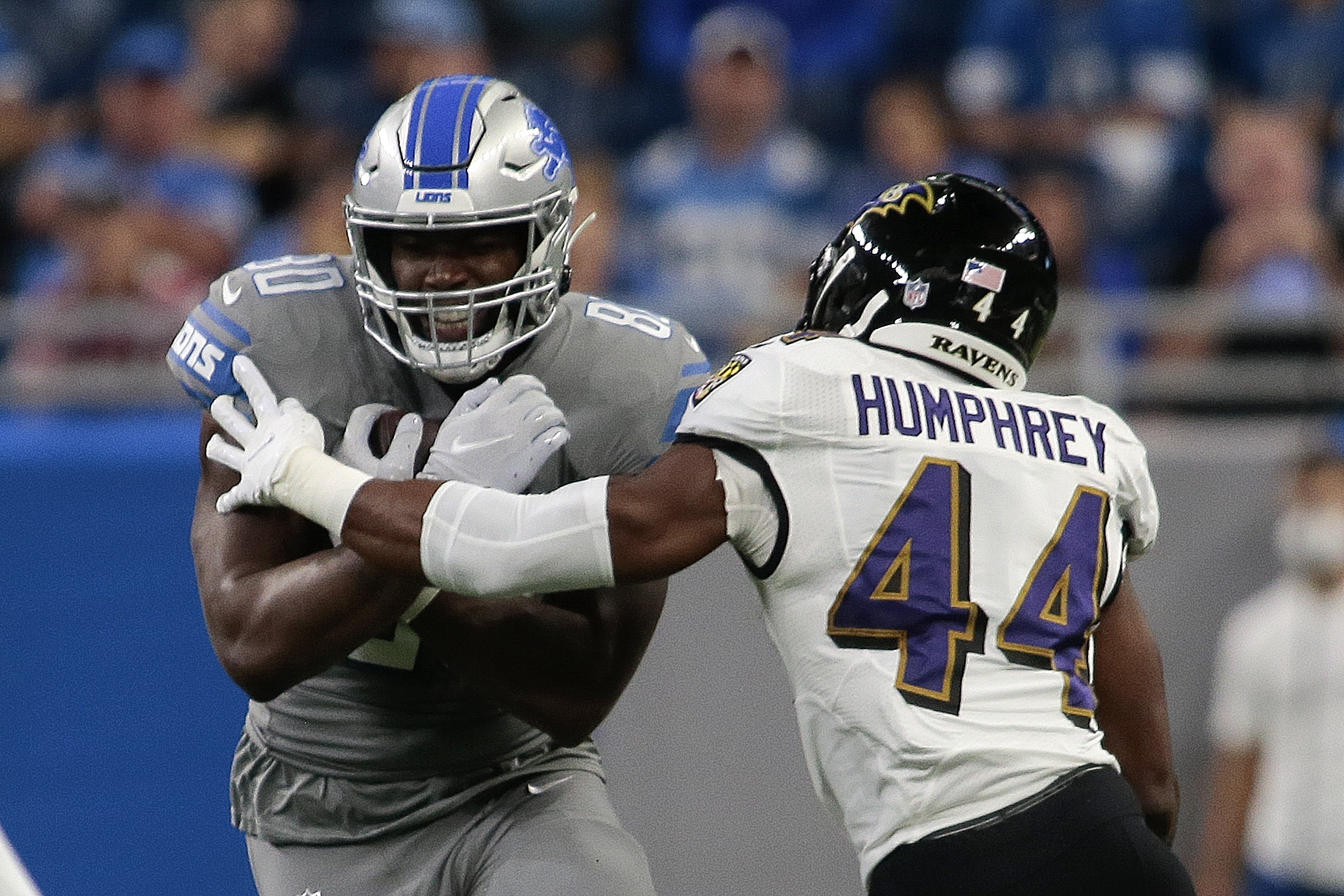 Detroit Lions tight end Darren Fells (80) tries to avoid Baltimore Ravens cornerback Marlon Humphrey (44) in the first half of an NFL football game in Detroit, Sunday, Sept. 26, 2021. (AP Photo/Tony Ding)