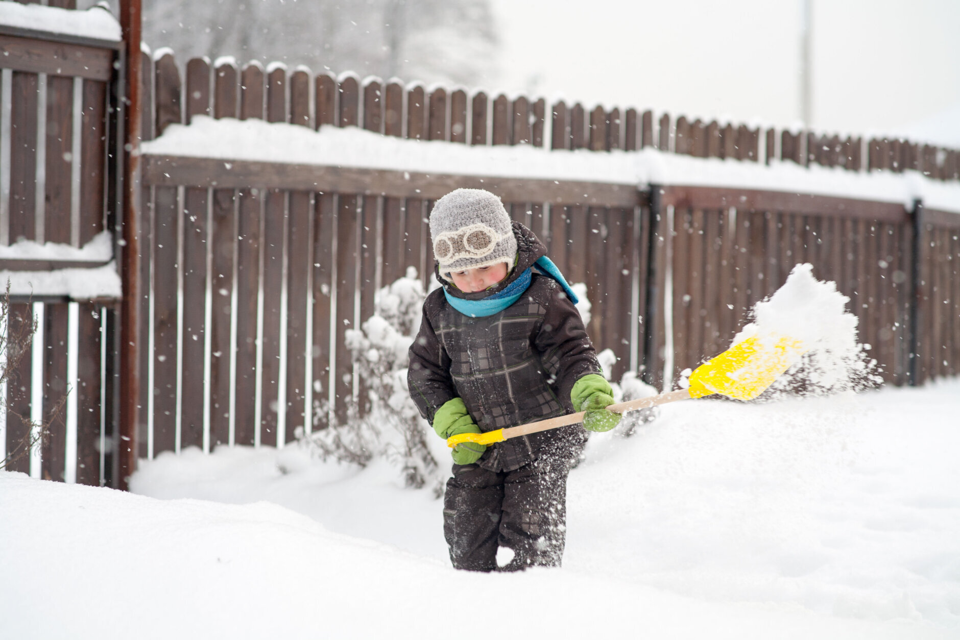 A little boy cleans a shovel paths in the yard from snow