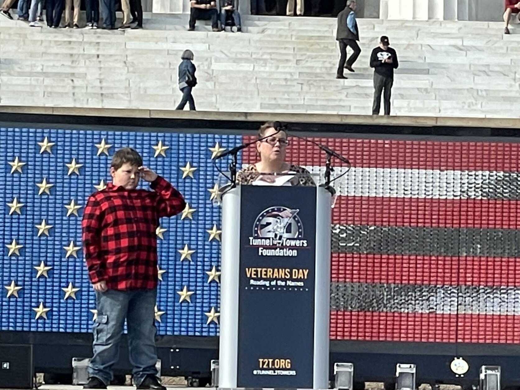 Diane LaRue reads names as her son, Seth Mendelsohn, salute veterans.