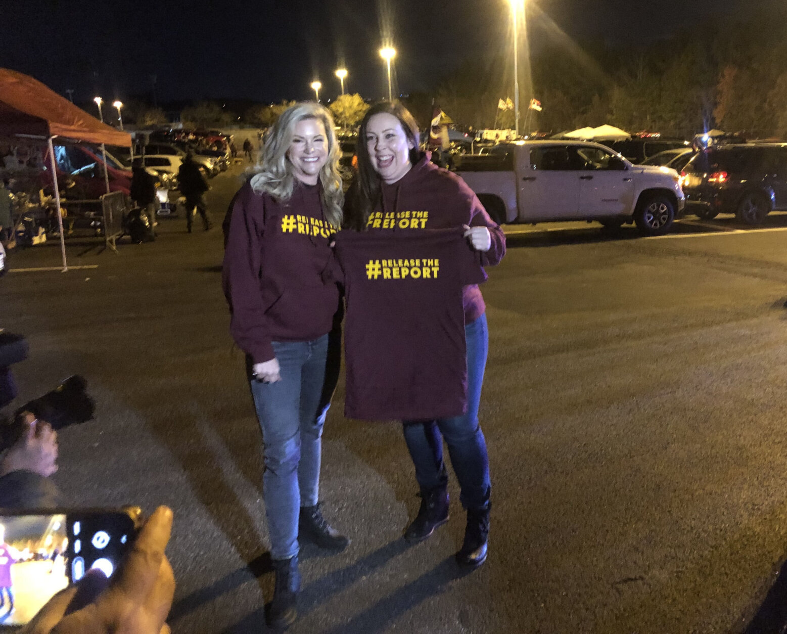 Melaine Coburn, left, and Megan Imbert, former employees of the Washington Football Team, poses for photos in the parking lot of FedEx Field before the start of an NFL game in Landover, Md. (WTOP/Dick Uliano)