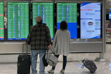 Travelers check the flight board at Dulles International Airport in Loudoun County, Virginia. (WTOP/Gigi Barnett)