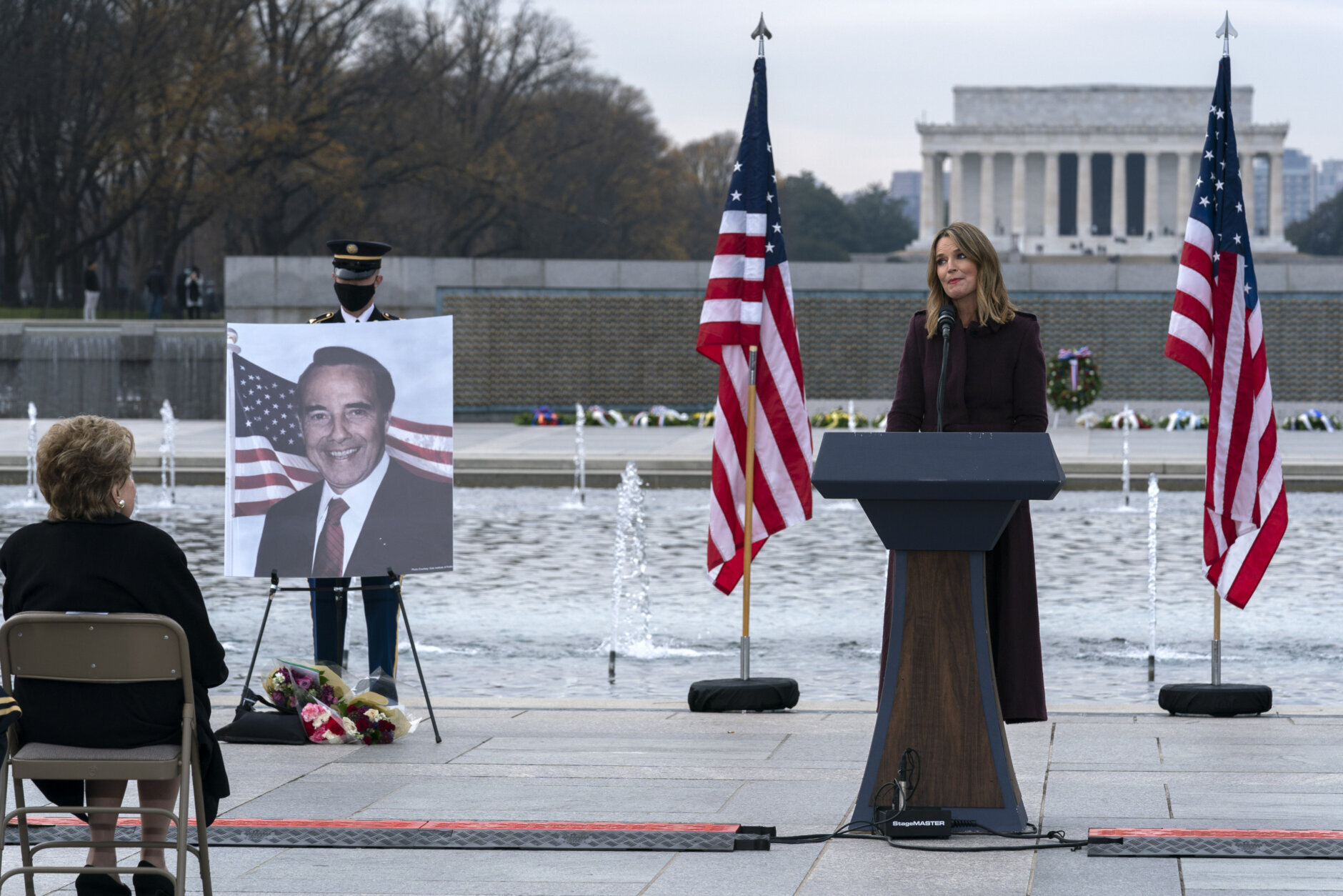With the Lincoln Memorial in the background, Savannah Guthrie speaks during a ceremony in honor to former Sen. Bob Dole, R-Kan. as former Sen. Elizabeth Dole looks on at the National World War II Memorial, on Friday, Dec. 10, 2021, in Washington. (AP Photo/Jose Luis Magana)