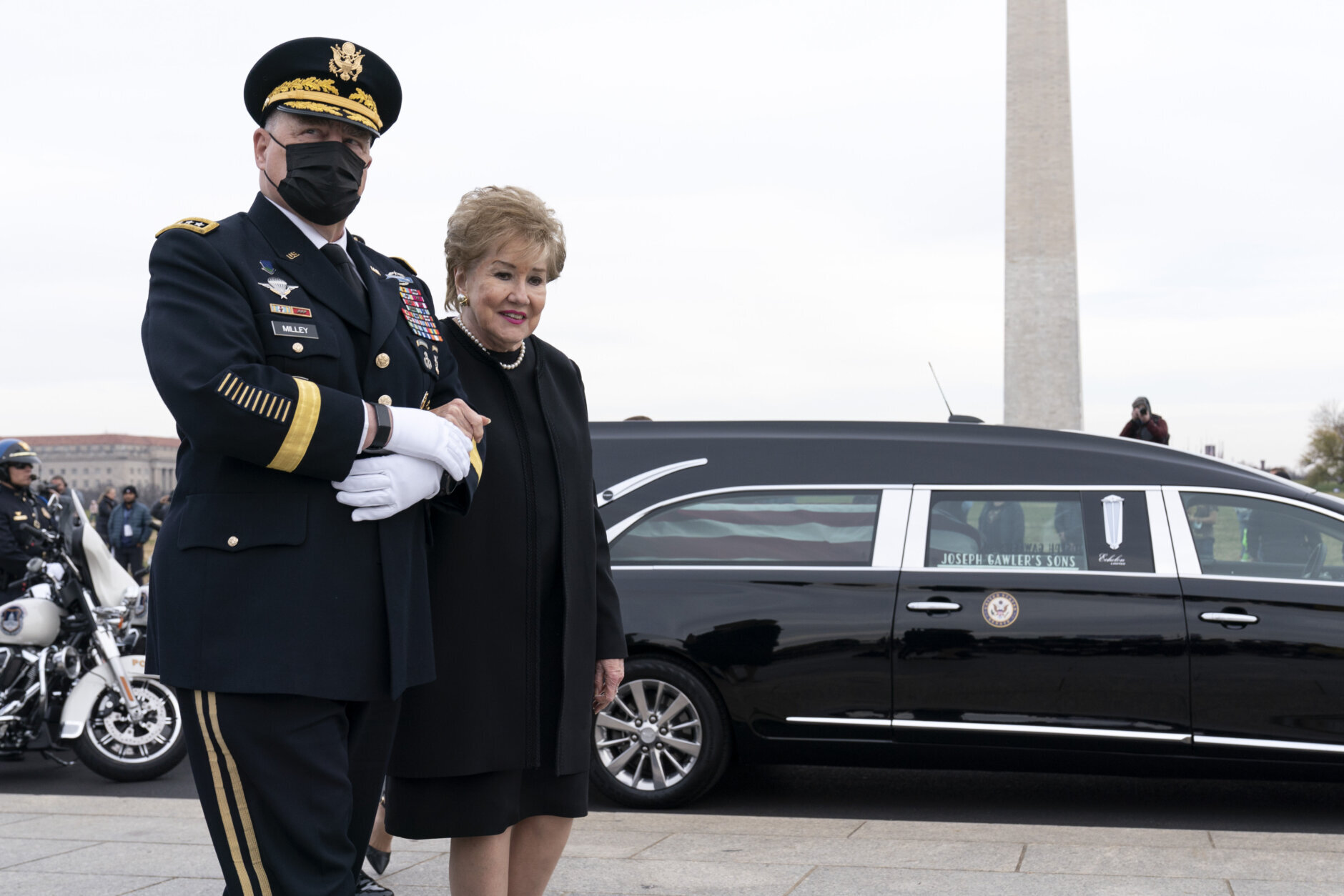 Former Sen. Elizabeth Dole accompanied by Chairman of the Joint Chiefs of Staff Gen. Mark Milley walk past her late husband's hearse during a floral wreath ceremony in honor of former Sen. Bob Dole, R-Kan. at the National World War II Memorial, on Friday, Dec. 10, 2021, in Washington. (AP Photo/Jose Luis Magana)