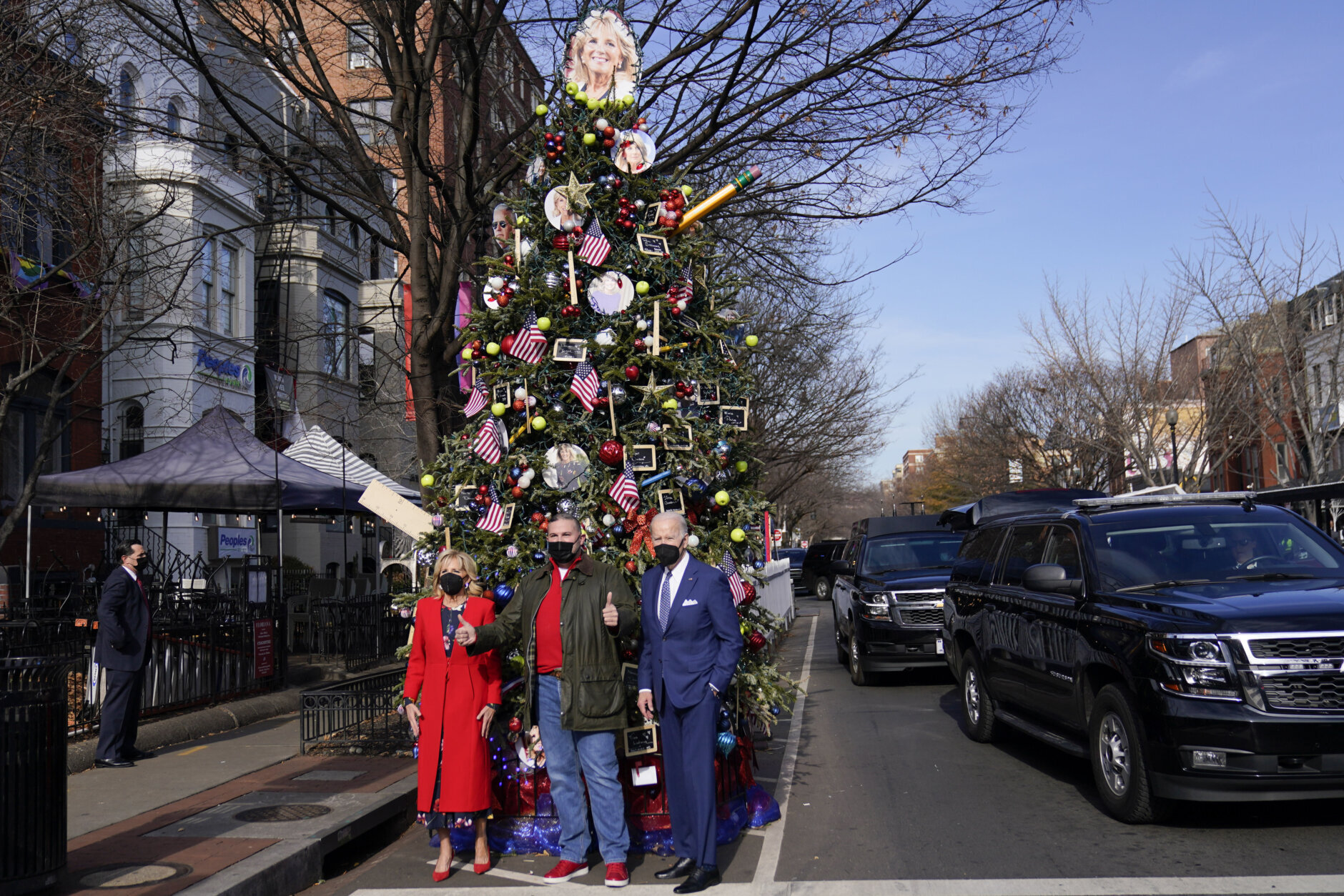 President Joe Biden and first lady Jill Biden pose for a photo with Dito Sevilla near a holiday tree at the Italian restaurant Floriana in Washington, Friday, Dec. 24, 2021. Since 2012 outside the restaurant, a holiday tree with a theme has been decorated and this year's tree has been decorated with images first lady Jill Biden and President Joe Biden. (AP Photo/Carolyn Kaster)