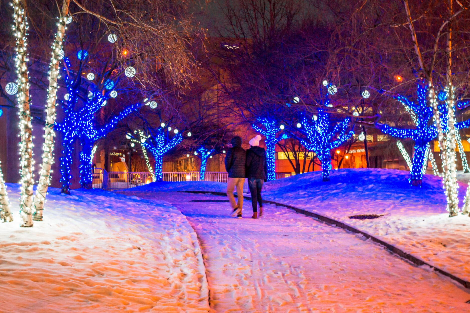 Couple walking through a park lit up for Christmas