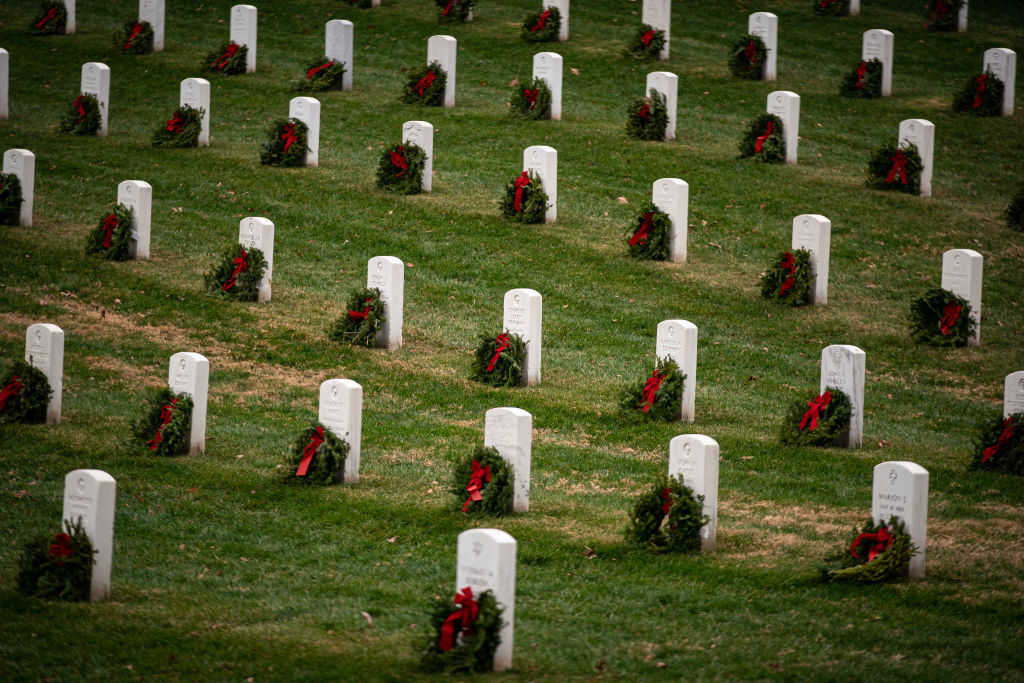 ARLINGTON, VA - DECEMBER 18: Balsam fir wreaths lie on tombstones at Arlington National Cemetery, on December 18, 2021 in Arlington, Virginia. The 30th annual Wreaths Across America project places wreaths on the more than 250,000 tombstones of military servicemen and women at Arlington National Cemetery. (Photo by Al Drago/Getty Images)