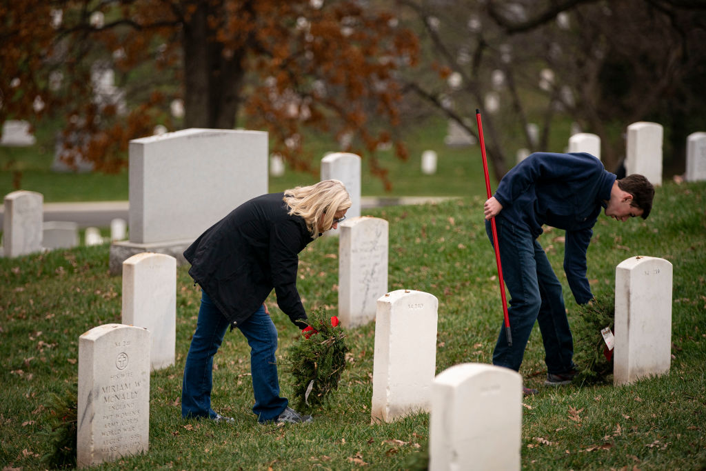 ARLINGTON, VA - DECEMBER 18: Rep. Liz Cheney (R-WY) places a wreath on a tombstone at Arlington National Cemetery, on December 18, 2021 in Arlington, Virginia. The 30th annual "Wreaths Across America" project places wreaths on the more than 250,000 tombstones of military servicemen and women at Arlington National Cemetery. (Photo by Al Drago/Getty Images)