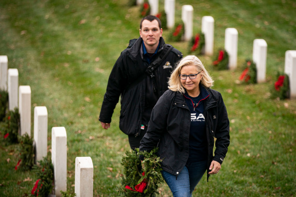 ARLINGTON, VA - DECEMBER 18: Rep. Liz Cheney (R-WY) carries a wreath to place on a tombstone at Arlington National Cemetery, on December 18, 2021 in Arlington, Virginia. The 30th annual "Wreaths Across America" project places wreaths on the more than 250,000 tombstones of military servicemen and women at Arlington National Cemetery. (Photo by Al Drago/Getty Images)