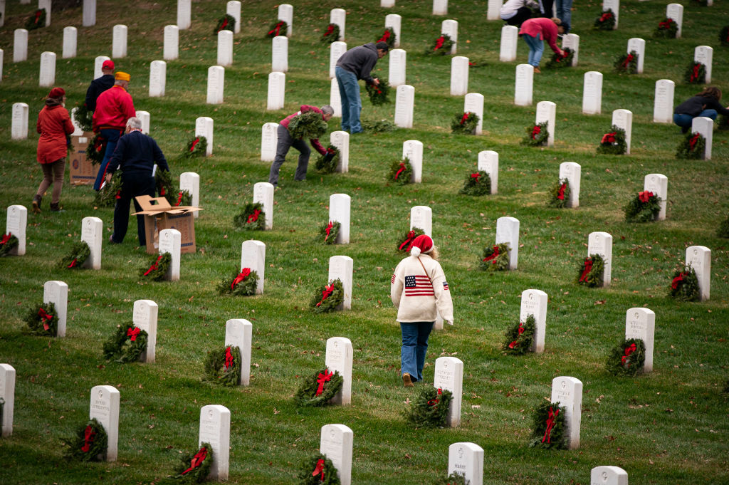 ARLINGTON, VA - DECEMBER 18: Volunteers place wreaths on tombstones at Arlington National Cemetery, on December 18, 2021 in Arlington, Virginia. The 30th annual "Wreaths Across America" project places wreaths on the more than 250,000 tombstones of military servicemen and women at Arlington National Cemetery. (Photo by Al Drago/Getty Images)