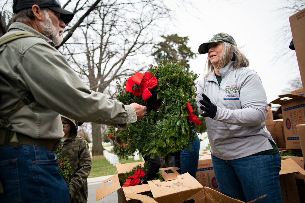 ARLINGTON, VA - DECEMBER 18: A volunteer distributes wreaths to be placed on tombstones at Arlington National Cemetery, on December 18, 2021 in Arlington, Virginia. The 30th annual "Wreaths Across America" project places wreaths on the more than 250,000 tombstones of military servicemen and women at Arlington National Cemetery. (Photo by Al Drago/Getty Images)