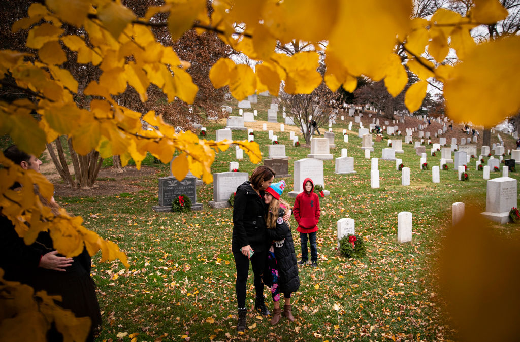ARLINGTON, VA - DECEMBER 18: People visit graves and  place wreaths on tombstones at Arlington National Cemetery, on December 18, 2021 in Arlington, Virginia. The 30th annual "Wreaths Across America" project places wreaths on the more than 250,000 tombstones of military servicemen and women at Arlington National Cemetery. (Photo by Al Drago/Getty Images)