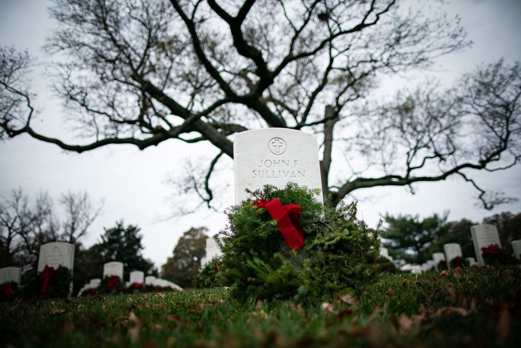 ARLINGTON, VA - DECEMBER 18: A Balsam fir wreath lies on a tombstone at Arlington National Cemetery, on December 18, 2021 in Arlington, Virginia. The 30th annual Wreaths Across America project places wreaths on the more than 250,000 tombstones of military servicemen and women at Arlington National Cemetery. (Photo by Al Drago/Getty Images)