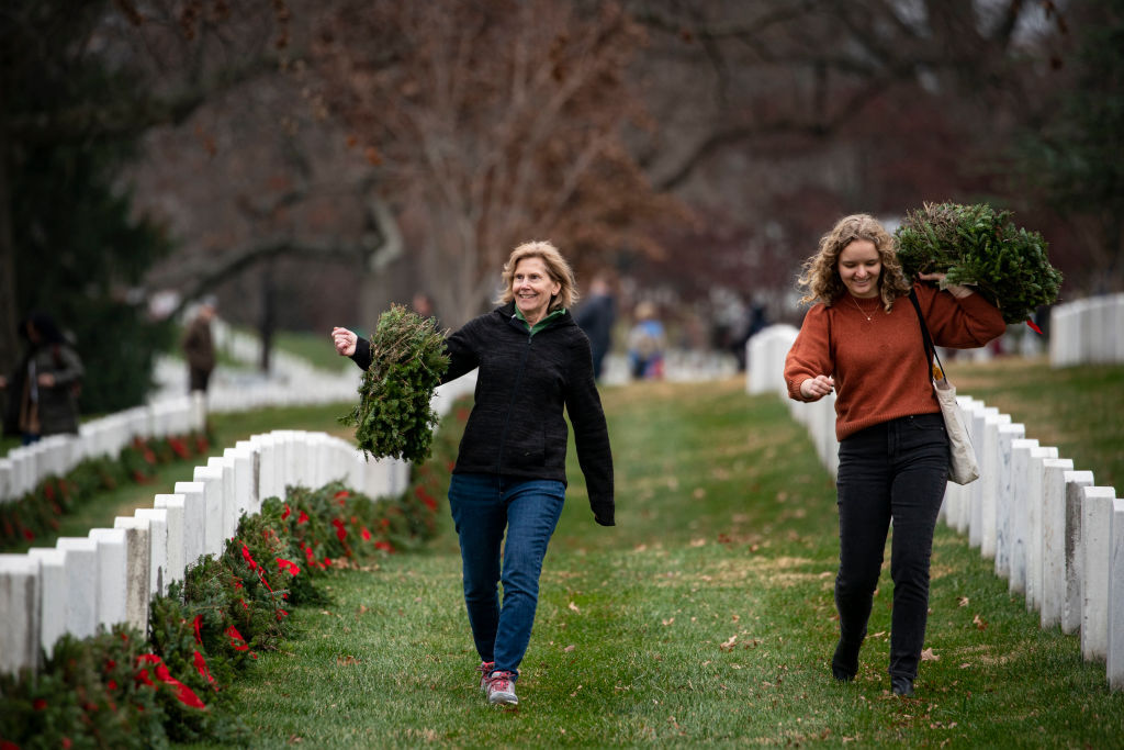 ARLINGTON, VA - DECEMBER 18: Volunteers carry wreaths to place on tombstones at Arlington National Cemetery, on December 18, 2021 in Arlington, Virginia. The 30th annual "Wreaths Across America" project places wreaths on the more than 250,000 tombstones of military servicemen and women at Arlington National Cemetery. (Photo by Al Drago/Getty Images)