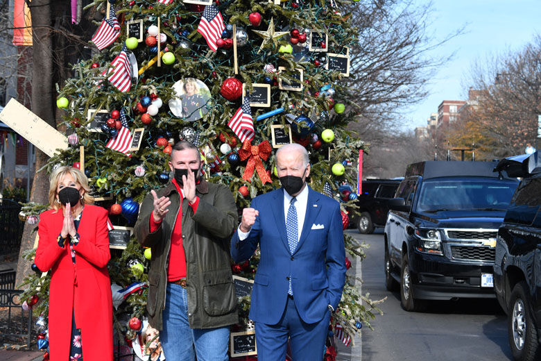 US President Joe Biden and First Lady Jill Biden pose with Dito Sevilla, bar manager of Floriana Italian Restaurant, in front of the Christmas Tree in honoring the First Lady, Washington, DC, on December 24, 2021. (Photo by Nicholas Kamm / AFP) (Photo by NICHOLAS KAMM/AFP via Getty Images)