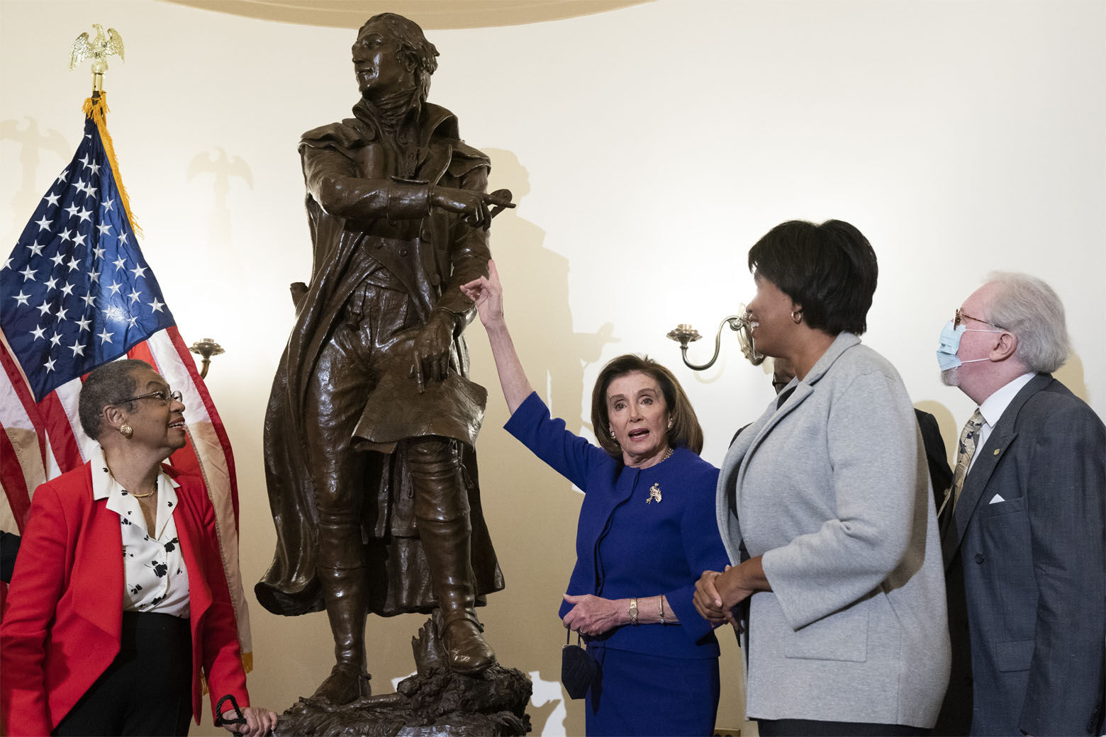 Speaker of the House Nancy Pelosi of Calif., points to new statue of Pierre L'Enfant, during a ceremony unveiling the statue, Monday, Feb. 28, 2022, at the Capitol in Washington. With her are Del. Eleanor Holmes Norton, D-D.C., left, District of Columbia Mayor Muriel Bowser, and artist Gordon Kray, far right, who sculpted the statue. (AP Photo/Jacquelyn Martin)