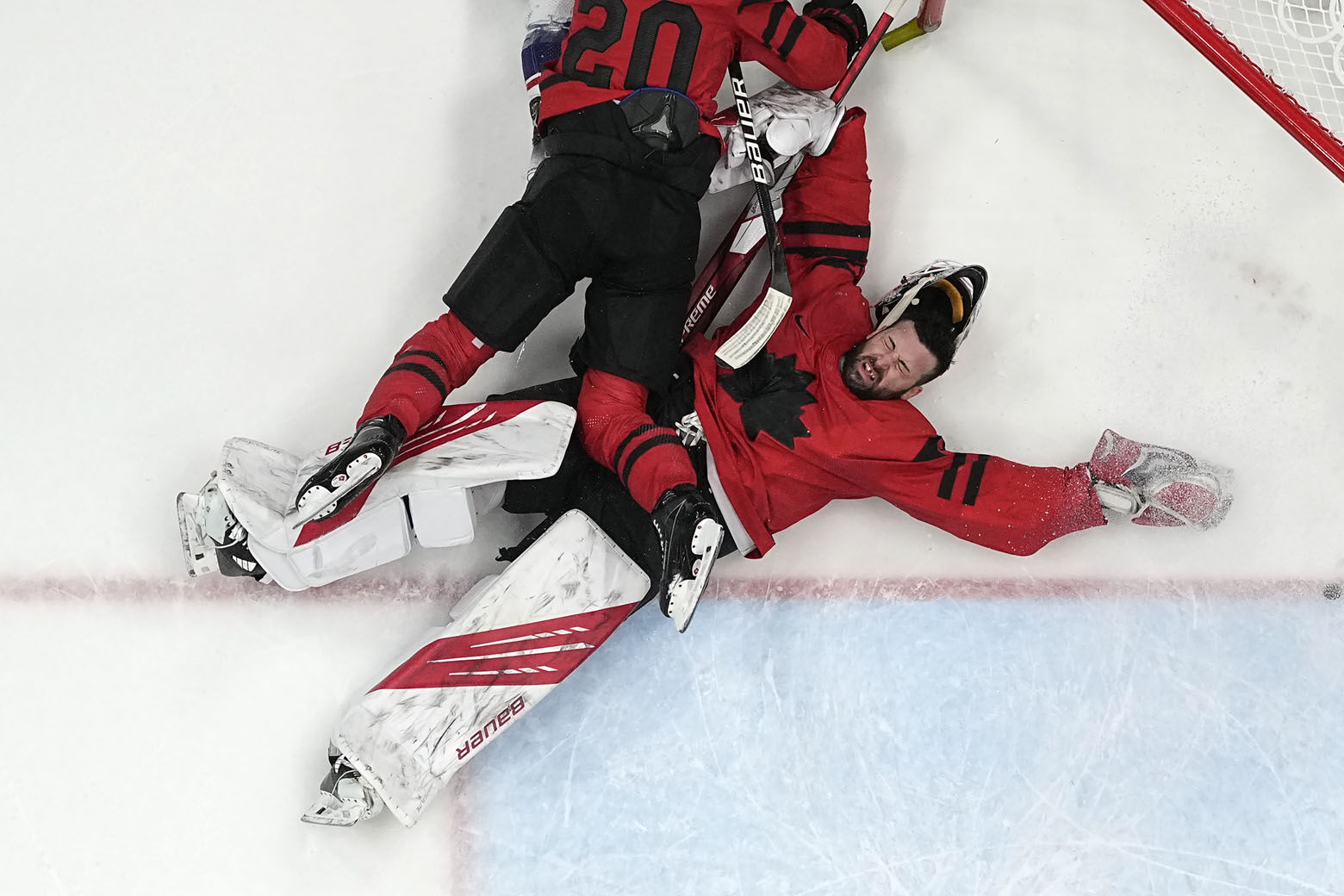 <p>Canada goalkeeper Eddie Pasquale is knocked down by teammate Alex Grant (20) during a preliminary round men&#8217;s hockey game against the United States at the 2022 Winter Olympics, Saturday, Feb. 12, 2022, in Beijing.</p>

