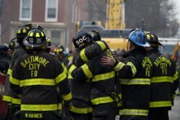 FILE - Firefighters embrace each other after a deceased firefighter was pulled out of a building collapse while battling a two-alarm fire in a vacant row home, Monday, Jan. 24, 2022, in Baltimore. Officials said several firefighters died during the blaze. The U.S. Census estimates there are 17 million vacant homes across the U.S. (AP Photo/Julio Cortez, File)