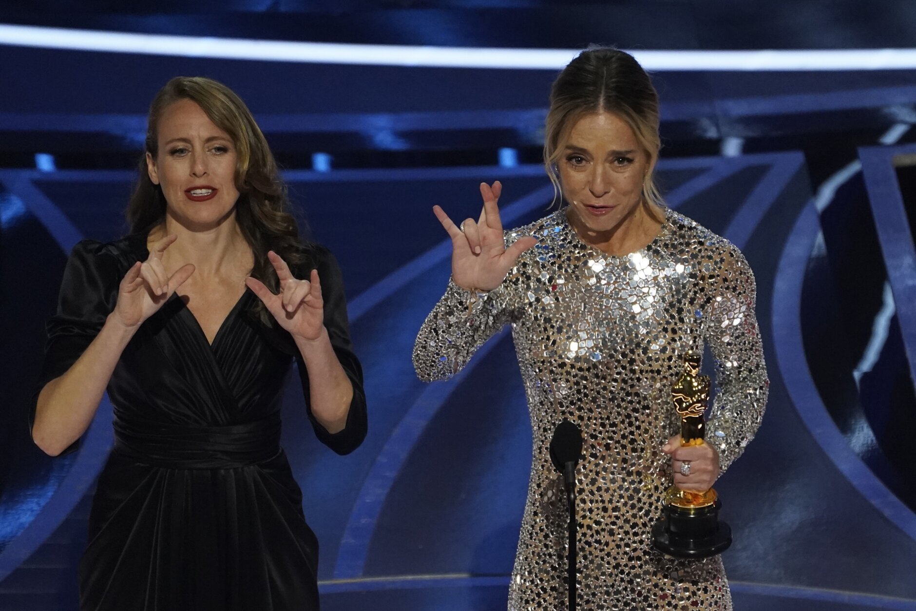 Sian Heder, right, signs "I really love you" as she accepts the award for best adapted screenplay for "CODA" at the Oscars on Sunday, March 27, 2022, at the Dolby Theatre in Los Angeles. (AP Photo/Chris Pizzello)