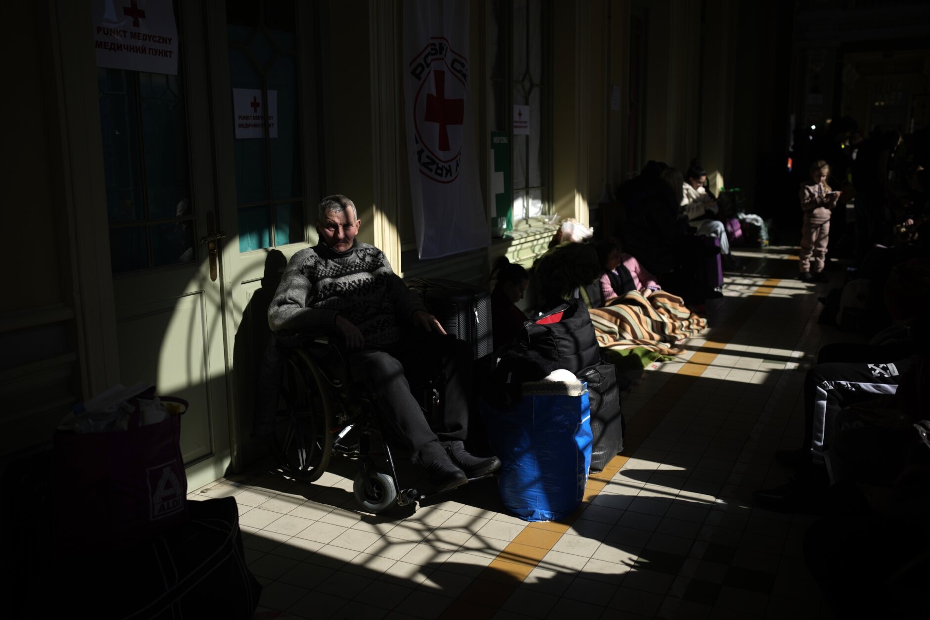 A Ukrainian sitting man in a wheel chair, waits with other refugees at Przemysl train station, southeastern Poland, on Friday, March 11, 2022. Thousands of people have been killed and more than 2.3 million have fled the country since Russian troops crossed into Ukraine on Feb. 24. (AP Photo/Daniel Cole)