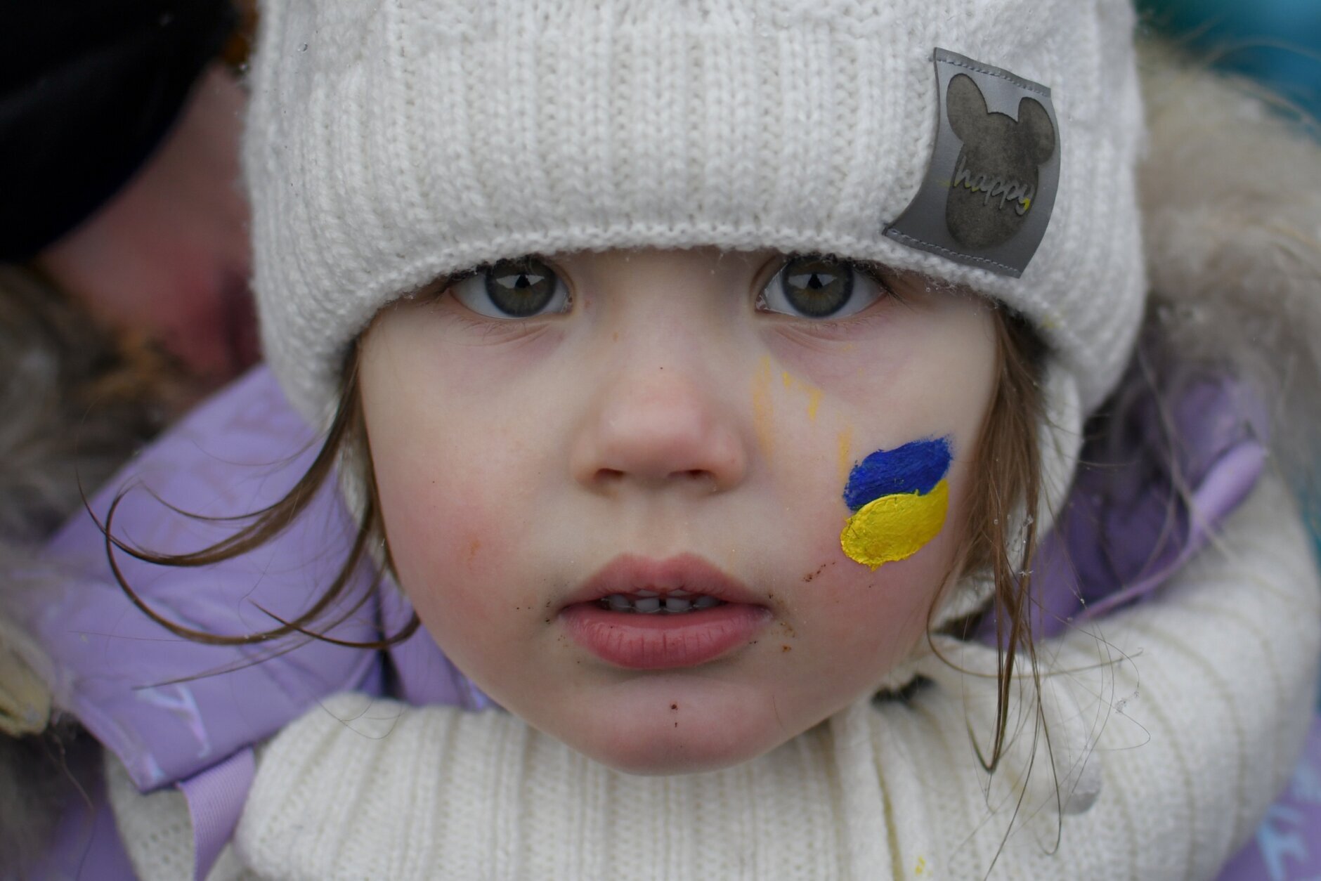 Zlata, 3 and half year-old, fleeing the conflict from neighbouring Ukraine with her face painted in the colours of the Ukrainian flag stands at the Romanian-Ukrainian border, in Siret, Romania, Thursday, March 3, 2022. The number of people sent fleeing Ukraine by Russia's invasion topped 1 million on Wednesday, the swiftest refugee exodus this century, the United Nations said, as Russian forces kept up their bombardment of the country's second-biggest city, Kharkiv, and laid siege to two strategic seaports. (AP Photo/Andreea Alexandru)