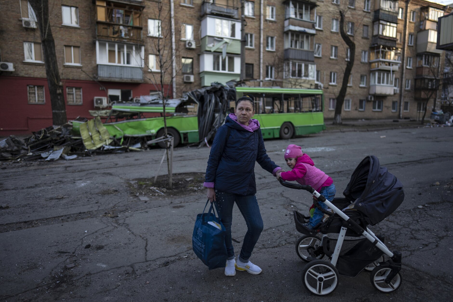Lena Danilova, 39, walks with her daughter Kira, 2, near her house in Podolskyi neighborhood, Kyiv, Ukraine, Friday, March 25, 2022. "I decided to stay, but since it continues so long, I don't think its safe any more, so I am working on leaving soon with my other two sons", said Lena to The Associated Press. (AP Photo/Rodrigo Abd)