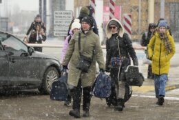 People carry their belongings after fleeing the war from neighbouring Ukraine, at the border crossing in Palanca, Moldova, Friday, March 11, 2022. (AP Photo/Sergei Grits)