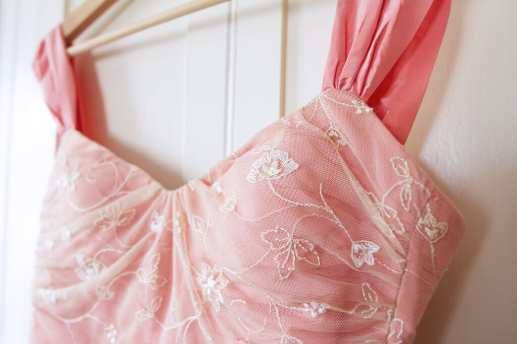 Close up of pink dress hanging on white door