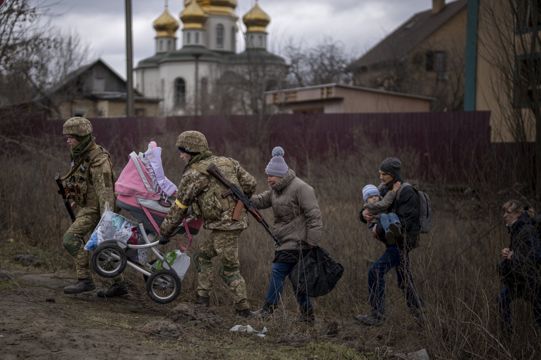 Ukrainian soldiers help a fleeing family crossing the Irpin river on the outskirts of Kyiv, Ukraine, Saturday, March 5, 2022. (AP Photo/Emilio Morenatti)
