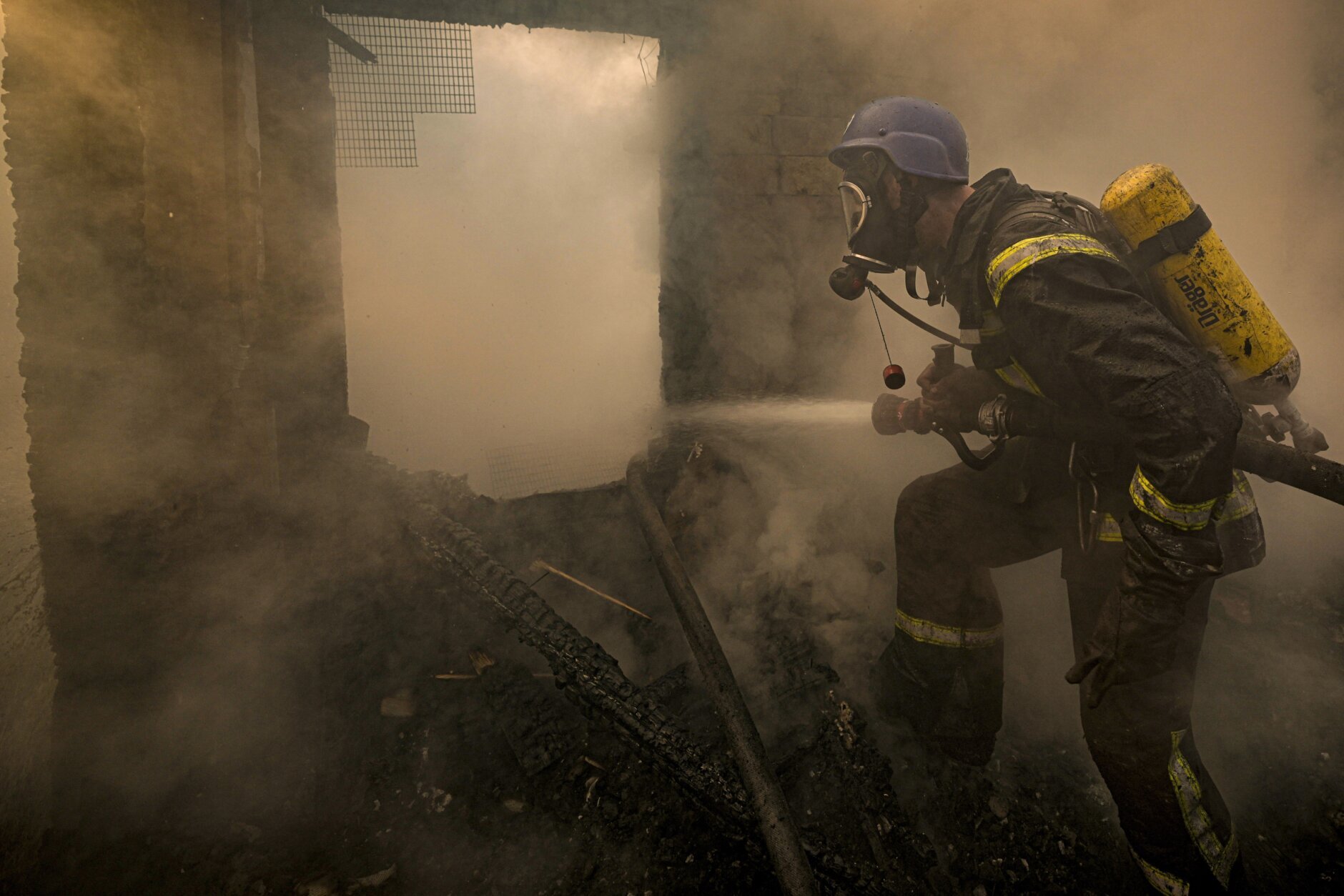 A Ukrainian firefighter sprays water inside a house destroyed by shelling, in Kyiv, Ukraine,Wednesday, March 23, 2022. The Kyiv city administration says Russian forces shelled the Ukrainian capital overnight and early Wednesday morning, in the districts of Sviatoshynskyi and Shevchenkivskyi, damaging buildings. (AP Photo/Vadim Ghirda)