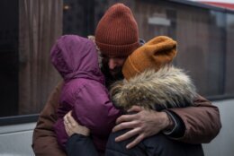 Ukrainian Pavlo Bilodid, 33, kisses his wife and daughter goodbye as they prepare to board a bus to Poland at Lviv bus main station, western Ukraine, Tuesday, March 1, 2022. Russian shelling pounded civilian targets in Ukraine's second-largest city Tuesday and a 40-mile convoy of tanks and other vehicles threatened the capital — tactics Ukraine’s embattled president said were designed to force him into concessions in Europe’s largest ground war in generations. (AP Photo/Bernat Armangue)