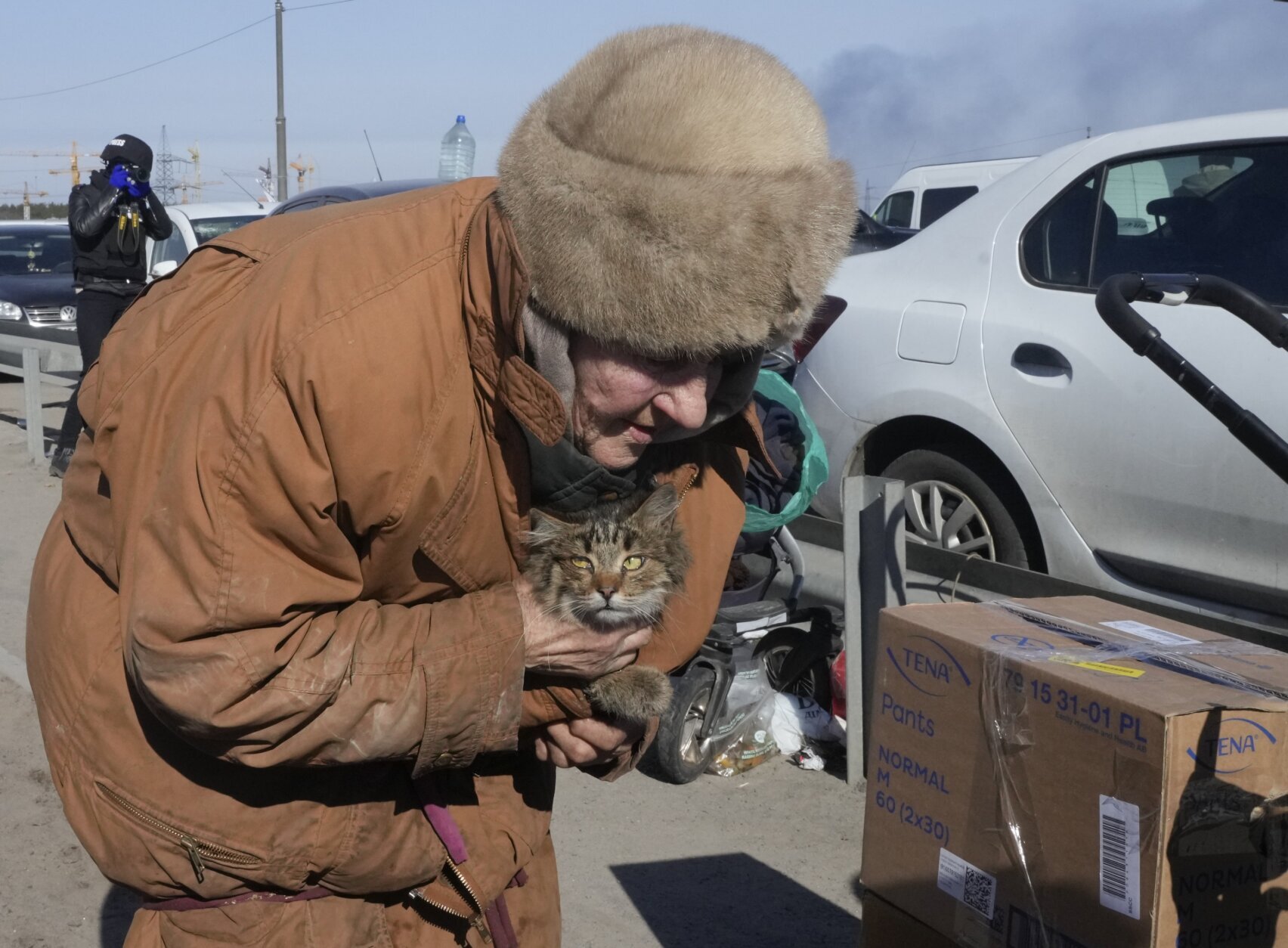 An elderly woman carries her cat as she flees from her hometown on the road towards Kyiv, in the town of Irpin, some 25 km (16 miles) northwest of Kyiv, Saturday, March 12, 2022. Kyiv northwest suburbs such as Irpin and Bucha have been enduring Russian shellfire and bombardments for over a week prompting residents to leave their homes. (AP Photo/Efrem Lukatsky)
