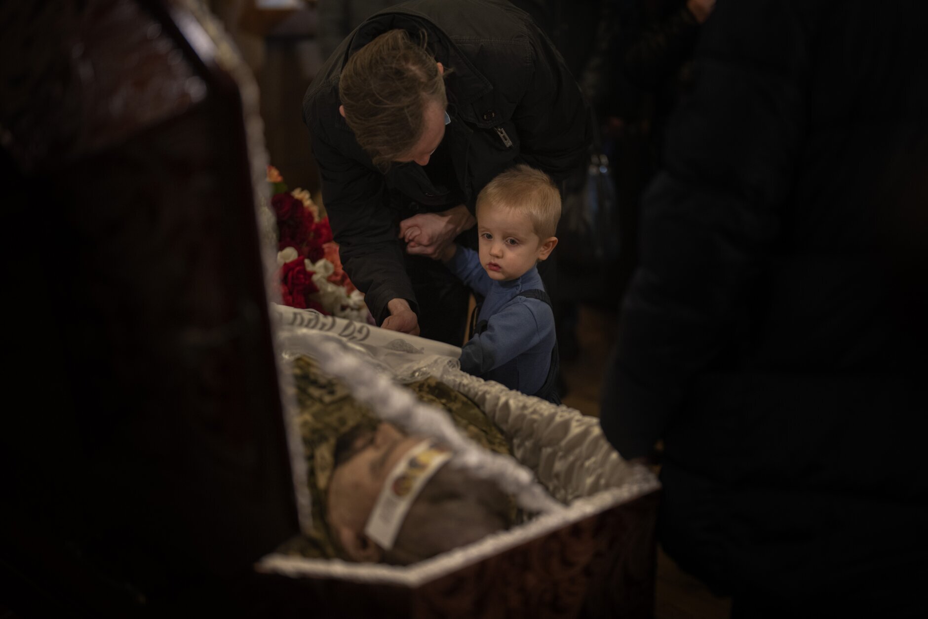 Serafim, 3, looks at the body of Ukrainian Army captain Anton Sydorov, 35, killed in eastern Ukraine, during his funeral, in Kyiv, Ukraine, Tuesday, Feb. 22, 2022. (AP Photo/Emilio Morenatti)
