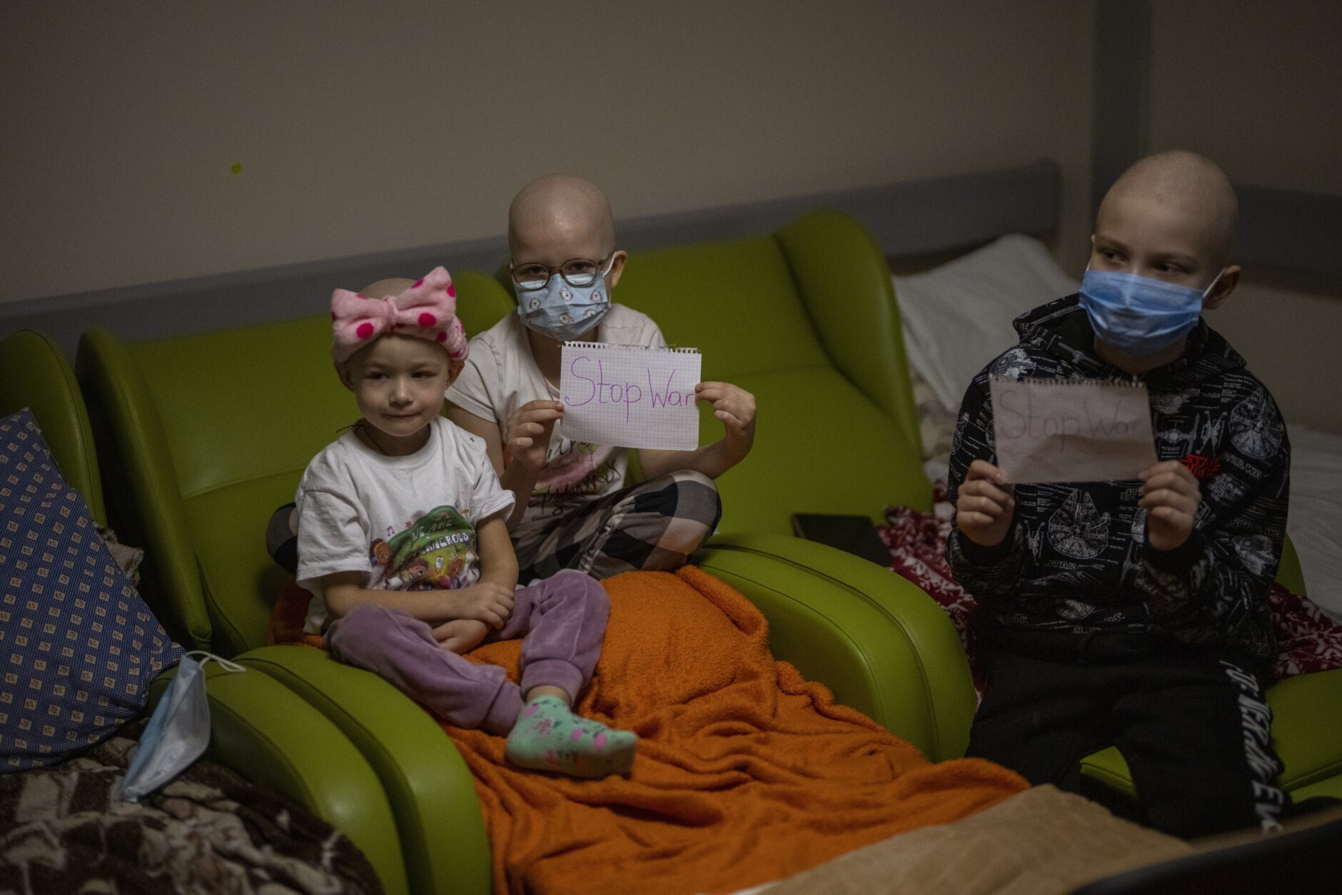 Oncology patients hold up sheets of paper with the words "Stop War" in a basement used as a bomb shelter at the Okhmadet children's hospital in central Kyiv, Ukraine, Monday, Feb. 28, 2022. (AP Photo/Emilio Morenatti)