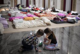 Children who fled the conflict from neighboring Ukraine play on the floor of an event hall in a hotel offering shelter in Siret, Romania, Saturday, Feb. 26, 2022. (AP Photo/Andreea Alexandru)