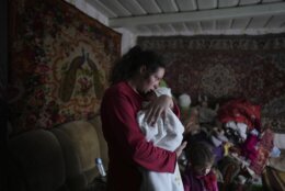 Anastasia Manha, 23, lulls her 2-month-old son Mykyta, where she lives with her family members, after shelling by separatists forces in Novognativka, eastern Ukraine, Sunday, Feb. 20, 2022. (AP Photo/Evgeniy Maloletka)