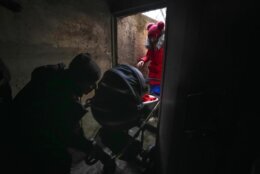 A couple enter a shelter with a baby in a stroller during Russian shelling outside Mariupol, Ukraine, Thursday, Feb. 24, 2022. (AP Photo/Sergei Grits)