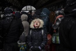 A girl catches snowflakes as she waits with others to board a train to Poland, at Lviv railway station, Sunday, Feb. 27, 2022, in Lviv, west Ukraine. (AP Photo/Bernat Armangue)